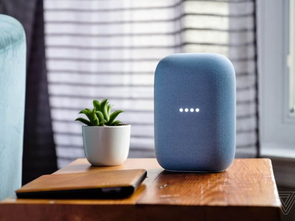 We zien een google nest op een houten bijzettafeltje staan. Deze kan voor Voice Search gebruikt worden, want de 4 lichtjes branden dus hij staat aan.